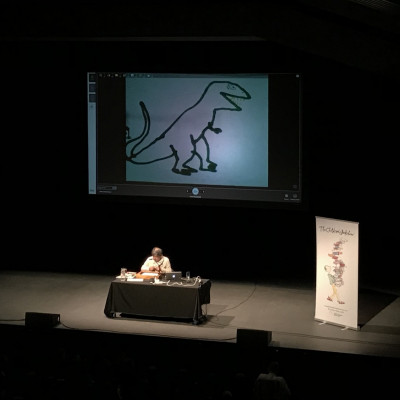 Satoshi draws a dinosaur on stage at Warwick Arts Centre