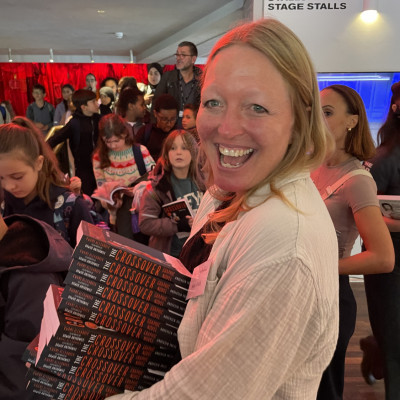 Kate Arafa handing out copies of *The Crossover* after a live event with Kwame Alexander at The Old Vic theatre. 890 children attended and they all went home with a free copy of the book.